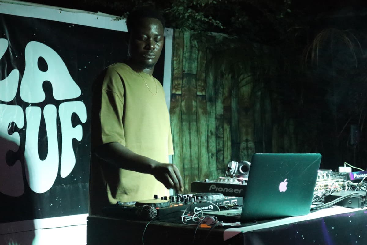 Un DJ derrière ses platines devant la bannière LA TEUF
